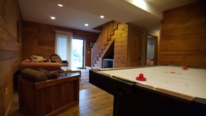 A cozy room with a pool table, wooden walls, a sofa, and a staircase leading to another level. - Overlook Cabin: E. Bluff Drive, Lake View, Hot Tub, Firepit, Central-AC, Private (Penn Yan)