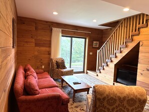 A wooden interior with a sofa, armchair, and a staircase. - Overlook Cabin: E. Bluff Drive, Lake View, Hot Tub, Firepit, Central-AC, Private (Penn Yan)