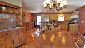 A spacious kitchen with wooden cabinets, a dining table, and a chandelier. - Overlook Cabin: E. Bluff Drive, Lake View, Hot Tub, Firepit, Central-AC, Private (Penn Yan)