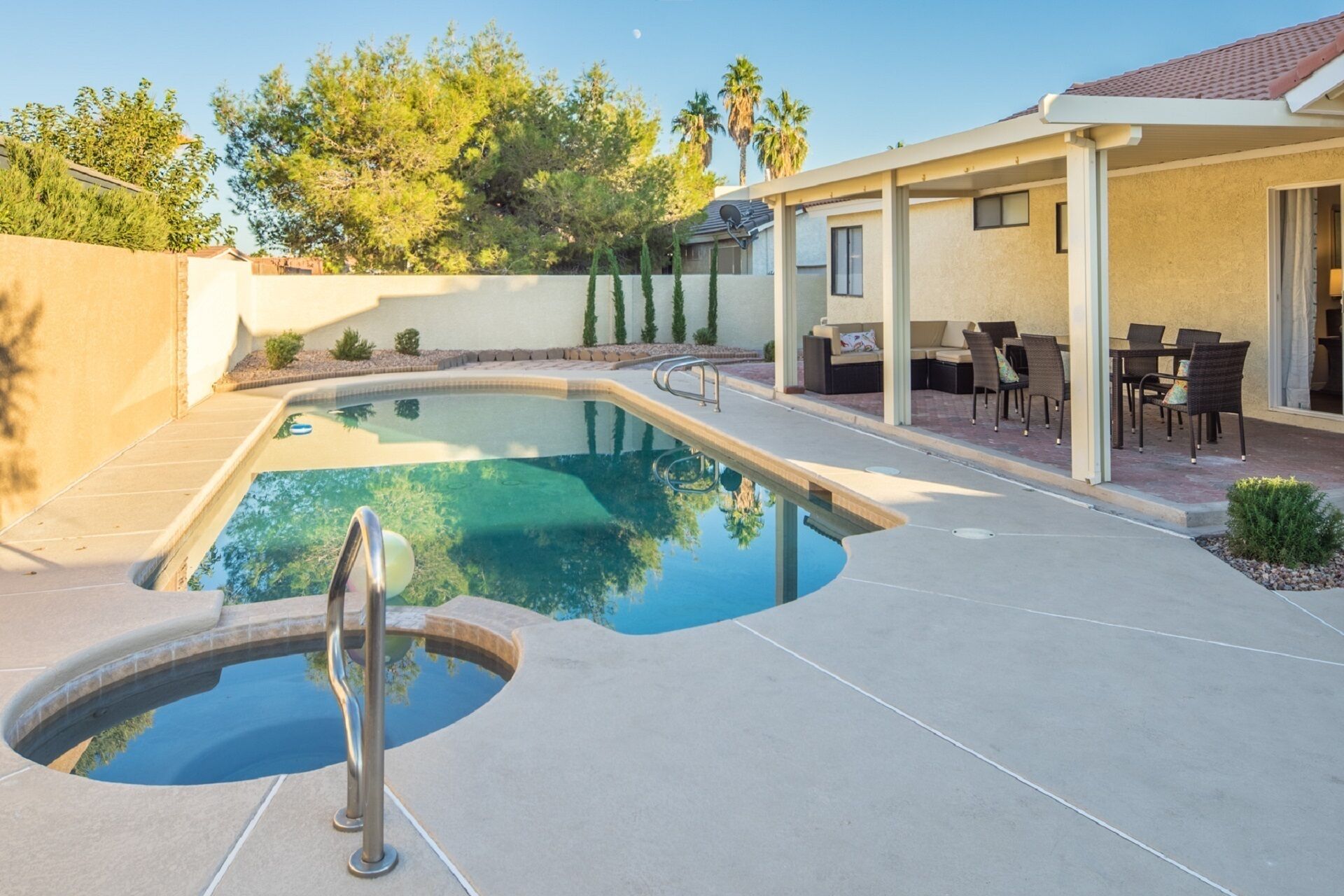 A swimming pool with a diving board, surrounded by a patio area with outdoor furniture.