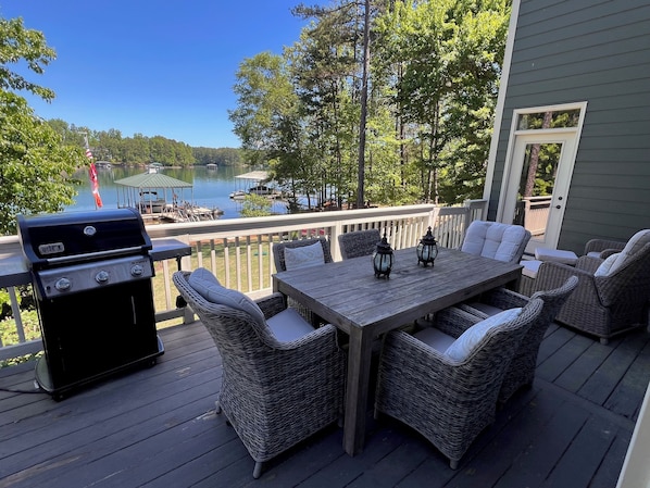 A deck with wicker furniture, a grill, and a view of a lake. - Lakefront Lake Keowee Home with flat lawn & private dock. 14 miles to Clemson! (Seneca)