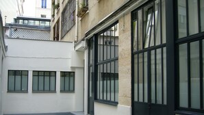 A courtyard with a bicycle, a stone floor, and large windows. - QUIET RENOVATED INDUSTRIAL LOFT IN "GRANDS BOULEVARDS" AREA; PARIS THEATRES AREA (Paris)