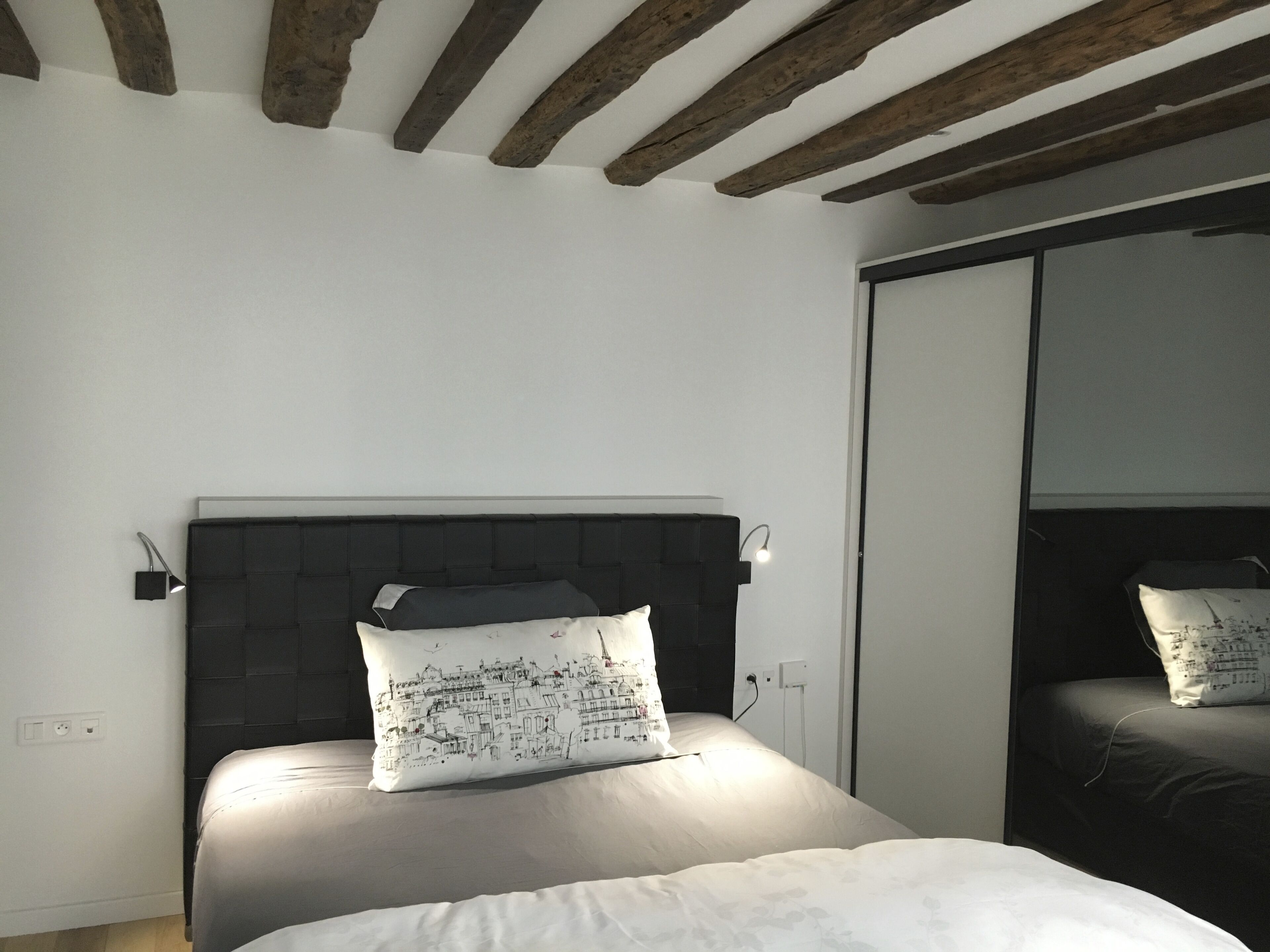 Ein Schlafzimmer mit einem Bett, einer Kopfteil, einer Wandleuchte und einer Steckdose.