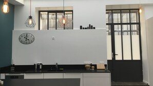 A modern kitchen with a black countertop, a built-in oven, and a clock on the wall. - QUIET RENOVATED INDUSTRIAL LOFT IN "GRANDS BOULEVARDS" AREA; PARIS THEATRES AREA (Paris)