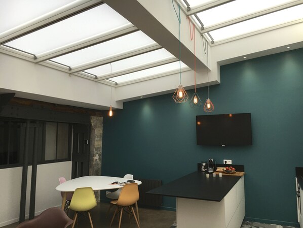 A modern kitchen with a black countertop, a built-in oven, and a microwave. There is a large window above the counter, and a flat-screen TV mounted on the wall. - QUIET RENOVATED INDUSTRIAL LOFT IN "GRANDS BOULEVARDS" AREA; PARIS THEATRES AREA (Paris)