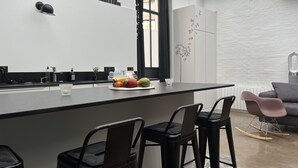 A modern kitchen with a central island, bar stools, a dining area with a sofa, and a decorative wall. - QUIET RENOVATED INDUSTRIAL LOFT IN "GRANDS BOULEVARDS" AREA; PARIS THEATRES AREA (Paris)