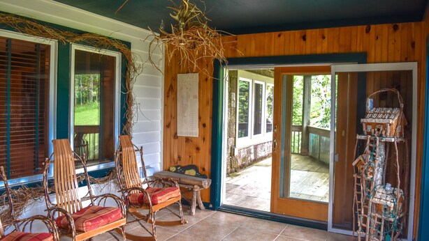 Una habitación con paredes de madera, una puerta corredera de vidrio que da al exterior y un comedero de pájaros a la derecha.