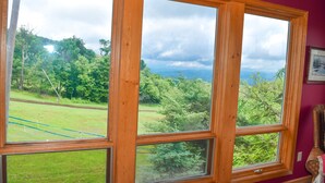 Una habitación con ventanas amplias que dan a un paisaje verde exuberante y un cielo nublado.