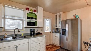 A compact kitchen with white cabinets, a stainless steel refrigerator, and a coffee maker. - Abba House Downtown  (Prescott)