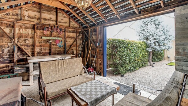 A rustic wooden interior with a covered patio area, a sofa, and a small table. - Abba House Downtown  (Prescott)