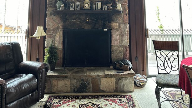 A stone fireplace with a mounted deer head, a fireplace mantel with decorative items, and a cozy seating area with a leather chair and a patterned rug. - Splendid European-Style Chalet w/ Game Room and Renovated Baths (McGaheysville)