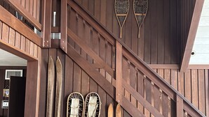 A wooden interior with a staircase, skis, and snowshoes hanging on the wall. - Splendid European-Style Chalet w/ Game Room and Renovated Baths (McGaheysville)