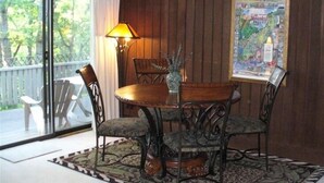 A dining area with a round table, four chairs, a lamp, and a map on the wall. - Splendid European-Style Chalet w/ Game Room and Renovated Baths (McGaheysville)