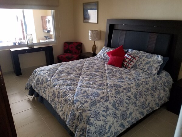 A bedroom with a large bed, a desk, a chair, and a window. - Gorgeous Poolside1-Bedroom Ocean View Condo #104 (El Divisadero)