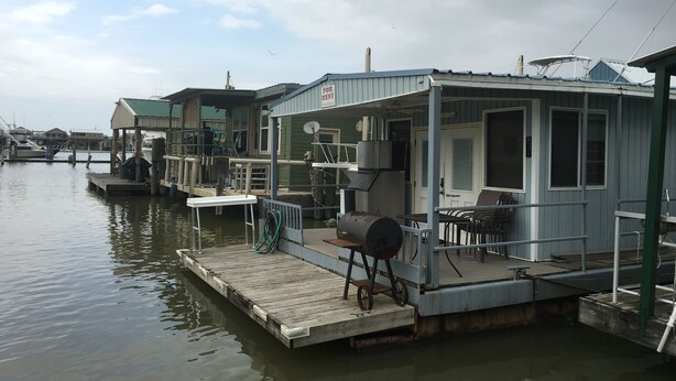 A waterfront property with a dock, a small building with a 'For Rent' sign, and a boat. - Houseboat Located In Venice Marina (Venice)