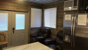 A compact kitchen with a marble countertop, two leather chairs, a refrigerator, and a window with blinds. - Houseboat Located In Venice Marina (Venice)