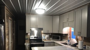 A modern kitchen with white cabinets, a stainless steel stove, a microwave, and a marble countertop. - Houseboat Located In Venice Marina (Venice)