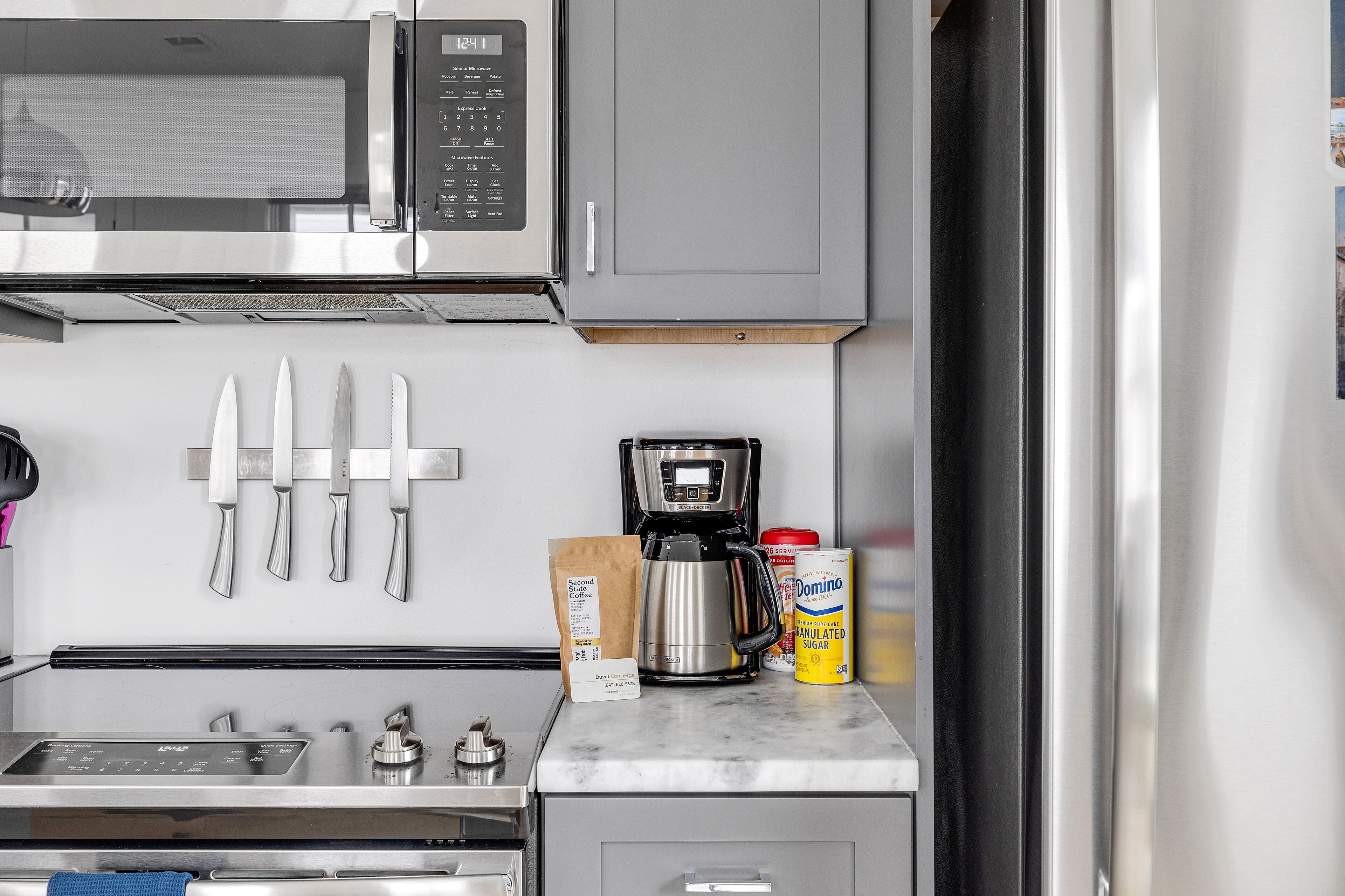 Una cocina con microondas, cafetera y una lata de café Domino instantáneo.