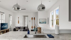 A modern kitchen with a large island, stainless steel appliances, and a view of the living area. - Charming Cozy Porch! | Globetrotter Suite D (Charleston)