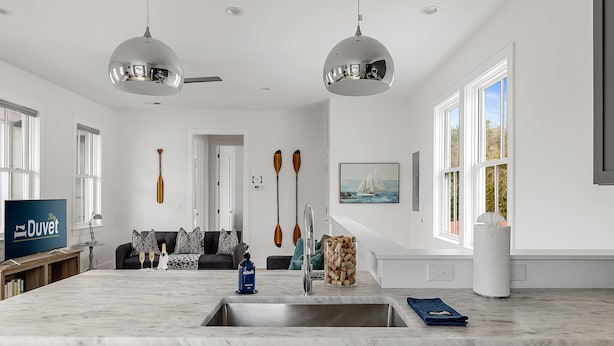 A modern kitchen with a large island, stainless steel appliances, and a view of the living area. - Charming Cozy Porch! | Globetrotter Suite D (Charleston)