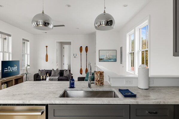 A modern kitchen with a large island, stainless steel appliances, and a view of the living area.