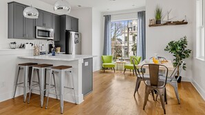 A modern kitchen with grey cabinets, stainless steel appliances, and a bar area. - Charming Cozy Porch! | Globetrotter Suite D (Charleston)