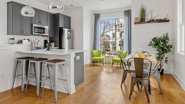 Una cucina moderna con mobili grigi, elettrodomestici in acciaio inossidabile e un'area bar.