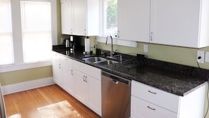 A kitchen with white cabinets, a black granite countertop, a dishwasher, and a window with blinds. - Casa Rustica - Centrally located, Carlsbad Caverns (Carlsbad)