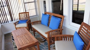 A wooden outdoor seating area with a table and chairs, a bench with blue cushions, and a patterned rug on the floor. - Casa Rustica - Centrally located, Carlsbad Caverns (Carlsbad)