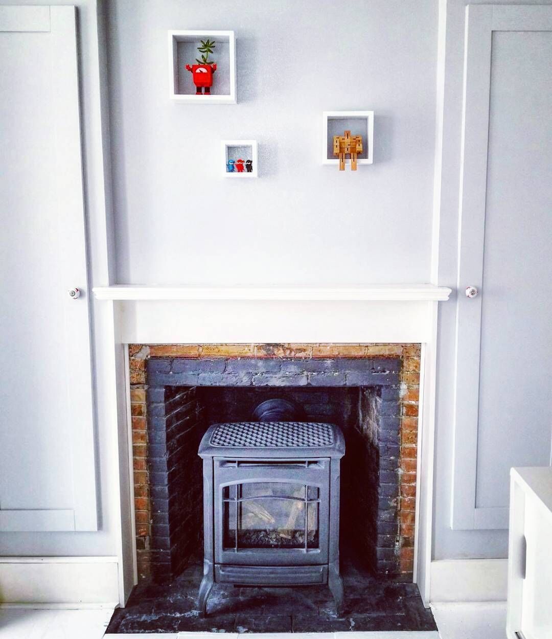 A fireplace with a white mantel and a brick surround, flanked by white doors.