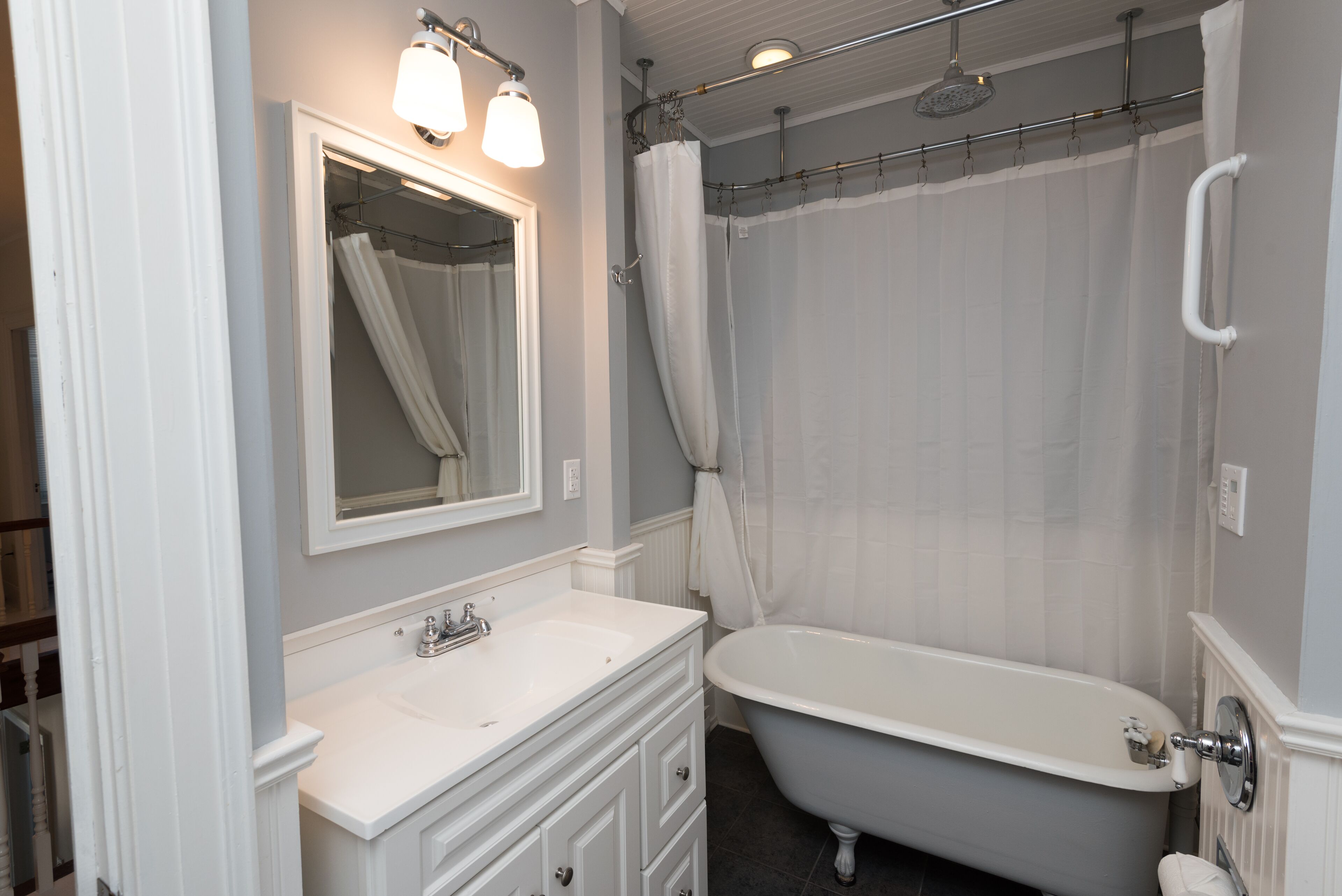 Un baño con una bañera blanca, un lavabo con espejo y una cortina de ducha.