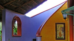 A staircase leading up to a room with a purple wall, a wooden bench, and large vases. - El Encanto - Artful Luxury in a Rustic Setting by the Sea (Cabo Pulmo)
