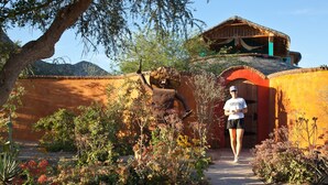 A pathway leading to a building with a thatched roof and a wooden balcony. - El Encanto - Artful Luxury in a Rustic Setting by the Sea (Cabo Pulmo)