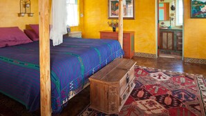 A room with a thatched roof, a bed with a colorful blanket, a wooden chest, and a patterned rug. - El Encanto - Artful Luxury in a Rustic Setting by the Sea (Cabo Pulmo)