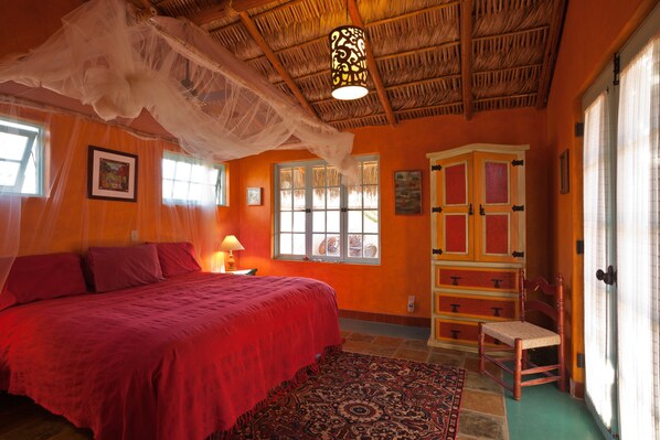 A room with a bed, a chair, a patterned rug, and a cabinet. - El Encanto - Artful Luxury in a Rustic Setting by the Sea (Cabo Pulmo)