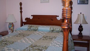 Una cama bien hecha con colcha floral, un cabecero de madera y dos lámparas de noche.