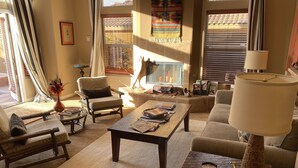 Un salon confortable avec un canapé, des fauteuils, une table basse et une lampe.