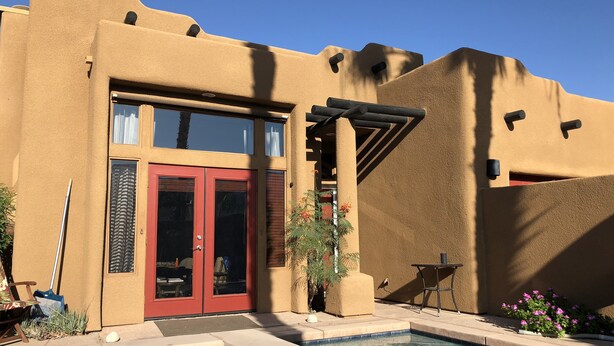 Un bâtiment doté d’une piscine, d’une porte rouge et d’une pergola.