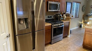 Une cuisine équipée d’appareils électroménagers en acier inoxydable, notamment un réfrigérateur, un four à micro-ondes, une cuisinière et un four.