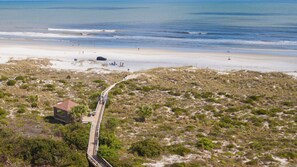 A beach with a wooden boardwalk leading to a small building, surrounded by dunes and sparse vegetation. - Ocean-Side 3BR/2BA Condo/Pool, Pickleball & Tennis The Villas of Ocean Gate 304 (St Augustine Beach)