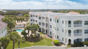 Hotel features a swimming pool surrounded by palm trees and lush greenery.