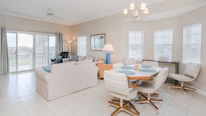 Relax in this spacious living room with a comfortable sofa, dining area, and large windows.