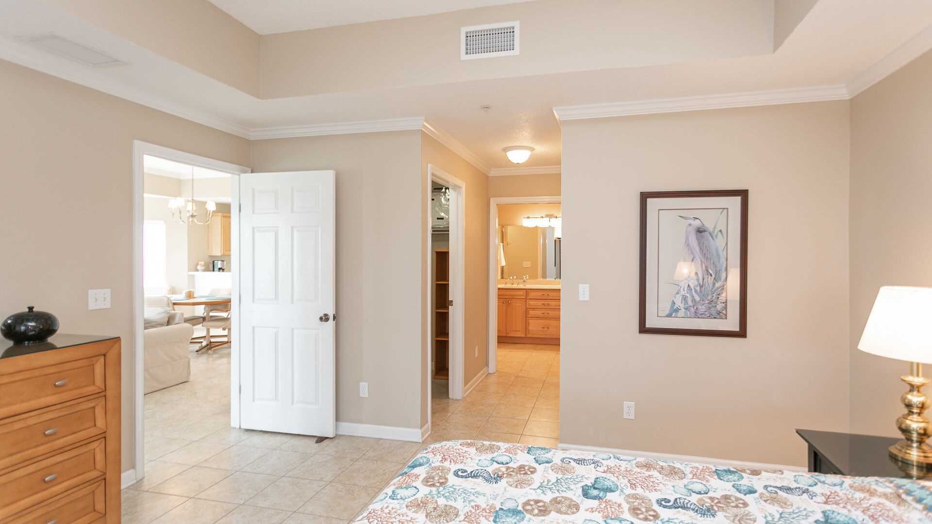 A bedroom with a bed, dresser, and a door leading to a bathroom.
