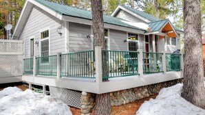Eine Holzhütte mit Steinfundament, einem grünen Metalldeck und einer Veranda mit Stühlen.
