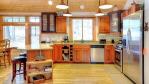 Eine Küche mit Holzausstattung, einem Edelstahlkühlschrank und einem Essbereich mit Holztischen und Stühlen.