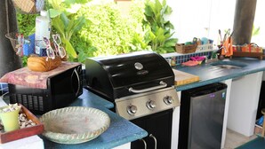 Eine kompakte Küche mit integriertem Grill, einem kleinen Kühlschrank und einer Spüle.