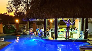 Relax by the pool surrounded by a thatched-roof bar and lounge area.