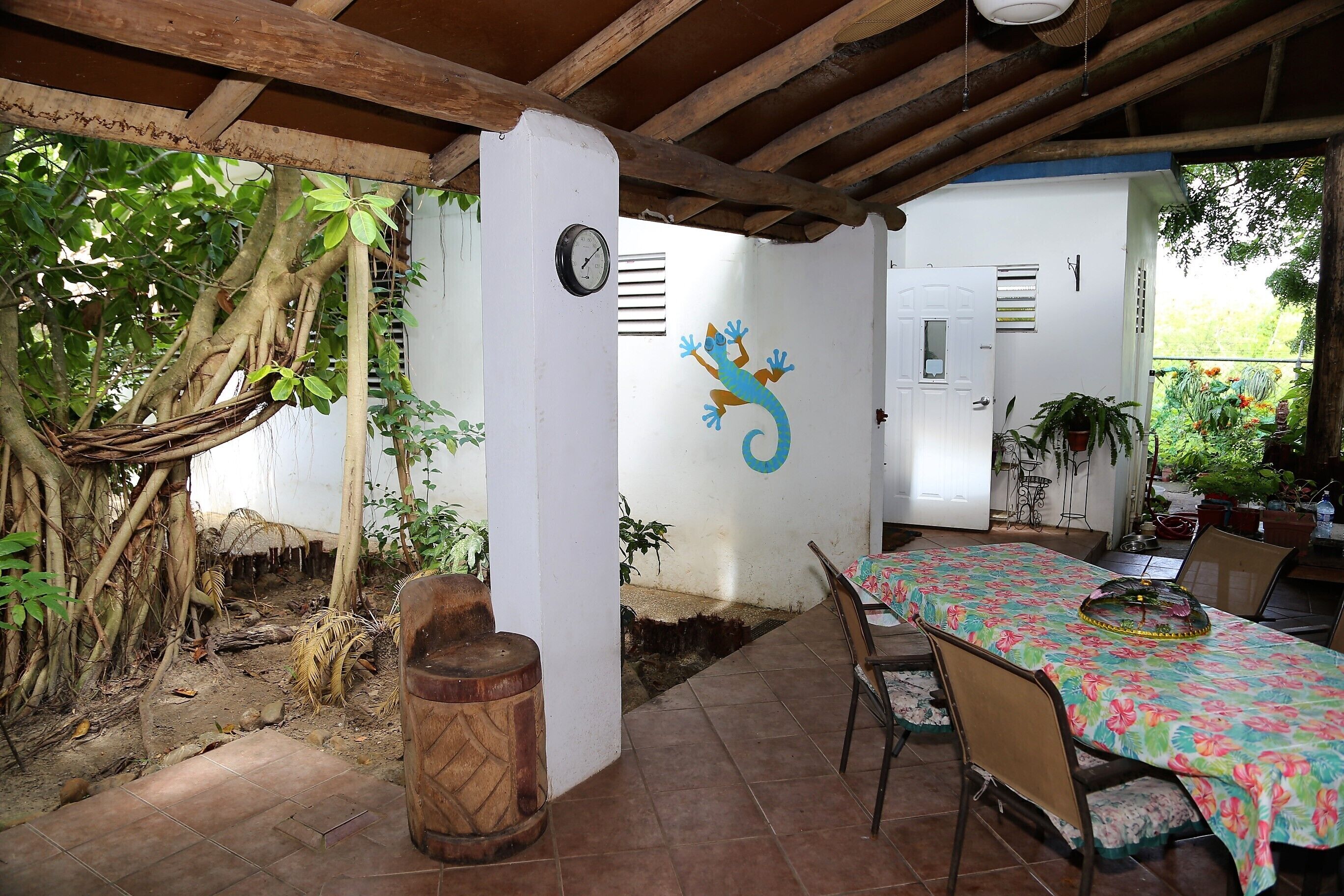 A covered patio with a dining table, chairs, and a hammock.