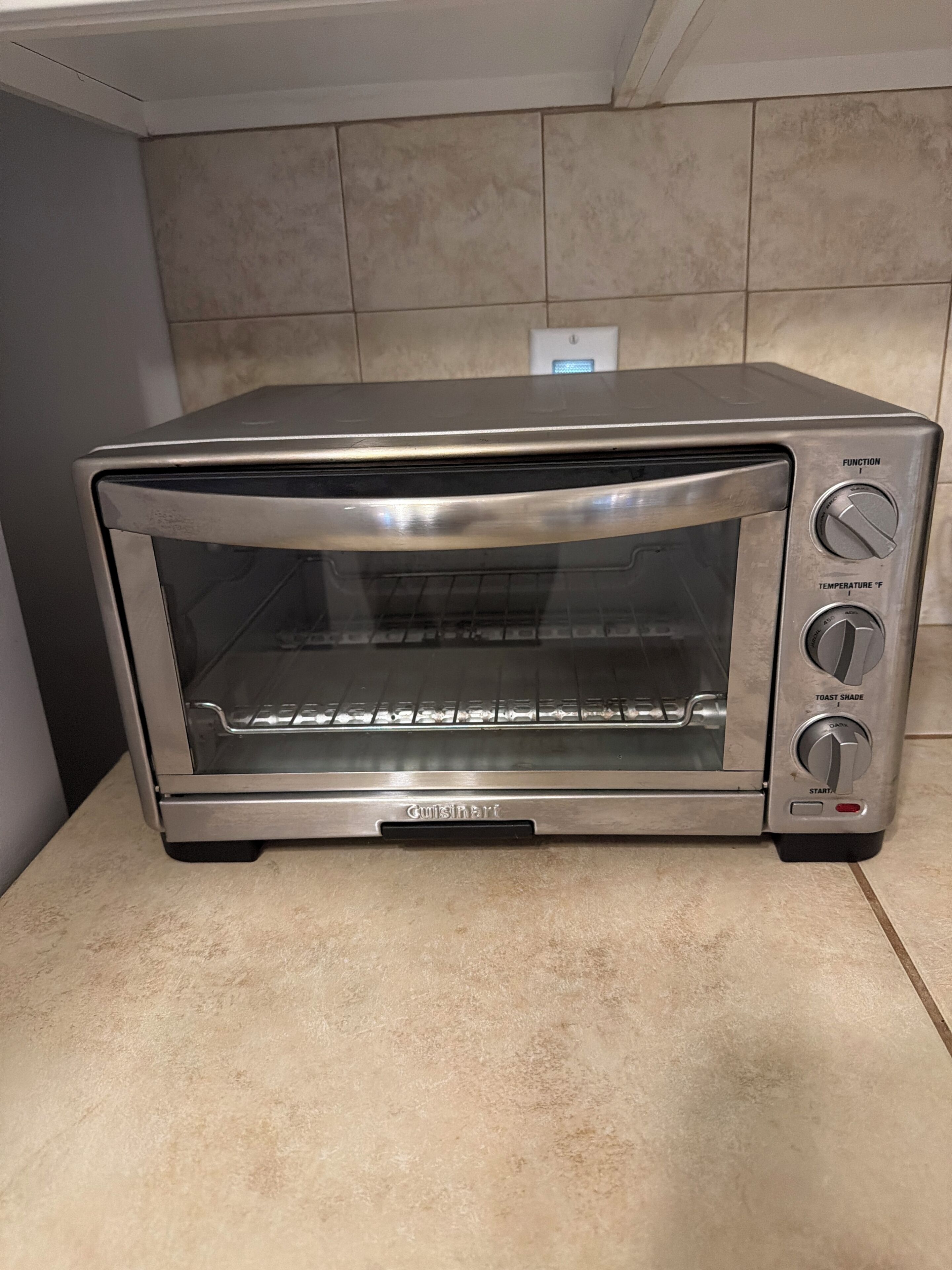 A stainless steel toaster oven with a digital display, control knobs, and a front glass door.