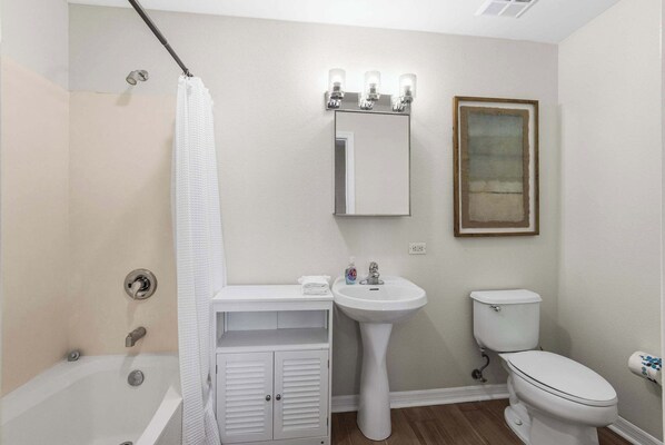 A bathroom with a bathtub, a sink, a toilet, and a shower curtain.